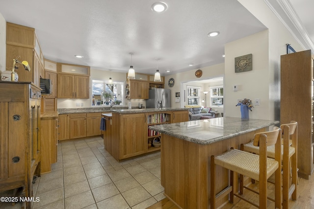 kitchen featuring a kitchen island, a kitchen bar, recessed lighting, a peninsula, and stainless steel fridge