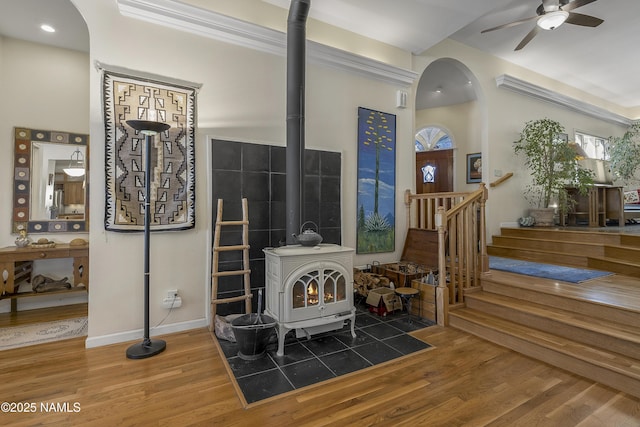 living area with arched walkways, a wood stove, and wood finished floors