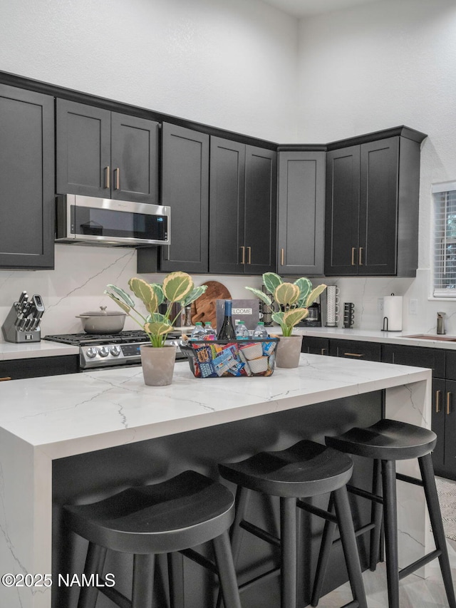 6136 E Abineau Canyon Dr, Flagstaff, AZ 86004 - kitchen featuring stainless steel microwave, a breakfast bar, range, light stone countertops, and dark cabinetry
