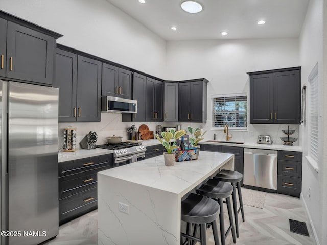 6136 E Abineau Canyon Dr, Flagstaff, AZ 86004 - kitchen featuring appliances with stainless steel finishes, a kitchen bar, a sink, a center island, and a towering ceiling