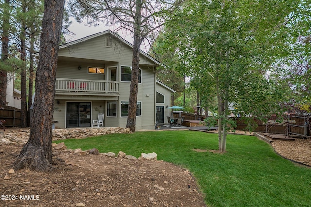 back of property featuring a balcony and a lawn