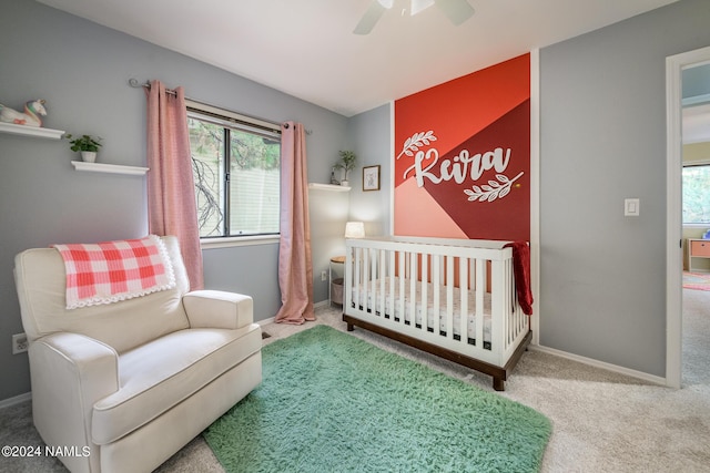 bedroom with ceiling fan, a nursery area, and carpet flooring