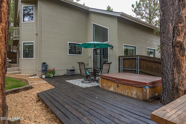 back of property featuring a wooden deck and a covered hot tub