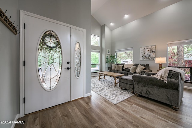 foyer with light wood-type flooring and high vaulted ceiling