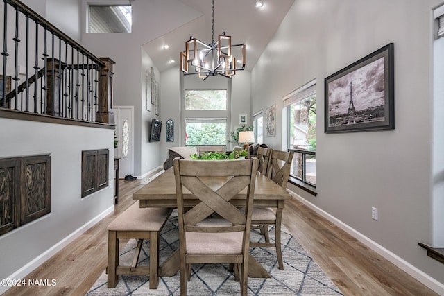 dining room featuring light wood-type flooring, a towering ceiling, and an inviting chandelier