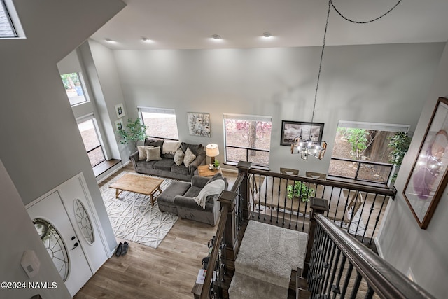 living room with a notable chandelier, a high ceiling, and light hardwood / wood-style flooring