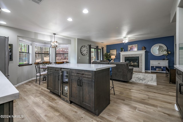 kitchen with a center island, wine cooler, light hardwood / wood-style floors, hanging light fixtures, and dark brown cabinets