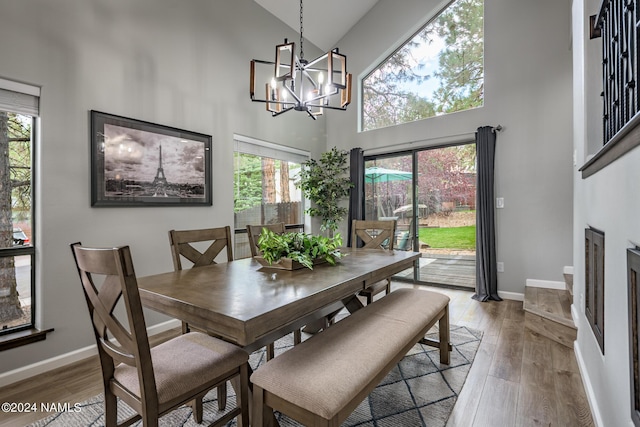 dining space with a chandelier, hardwood / wood-style flooring, and high vaulted ceiling