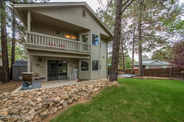 back of house featuring a balcony, a yard, and a patio