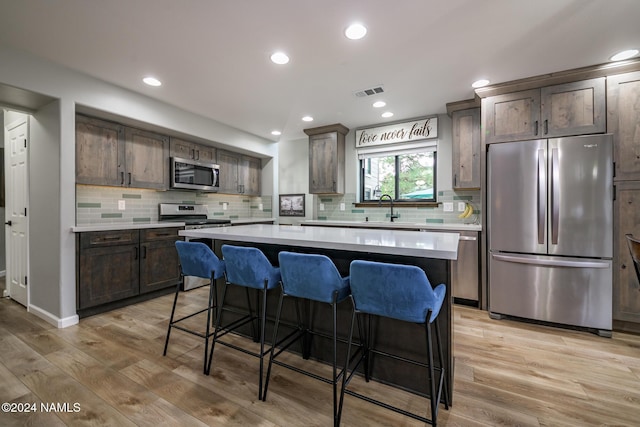 kitchen featuring dark brown cabinets, a center island, a kitchen bar, and stainless steel appliances