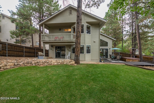 back of house with a balcony, a patio area, and a yard