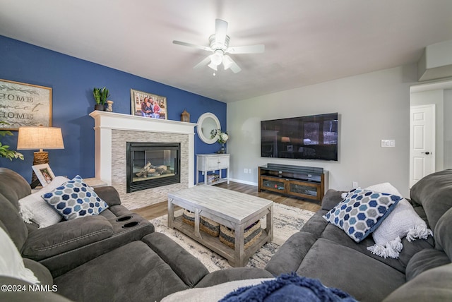 living room with ceiling fan, hardwood / wood-style floors, and a stone fireplace