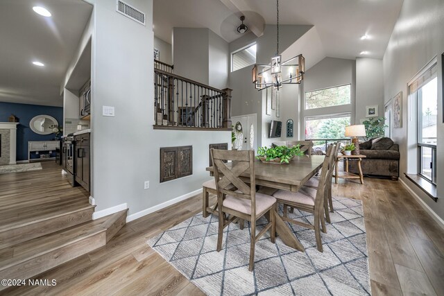 dining room featuring a high ceiling, light hardwood / wood-style flooring, a notable chandelier, and a fireplace