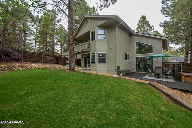 back of property featuring a balcony and a lawn