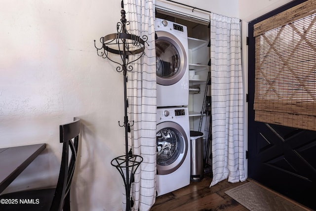 clothes washing area featuring dark wood-type flooring, laundry area, and stacked washing maching and dryer