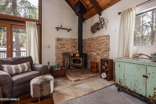 living area featuring beam ceiling, high vaulted ceiling, wood ceiling, and a wood stove