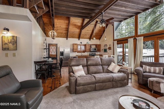 living area with beam ceiling, wood ceiling, a ceiling fan, and wood finished floors