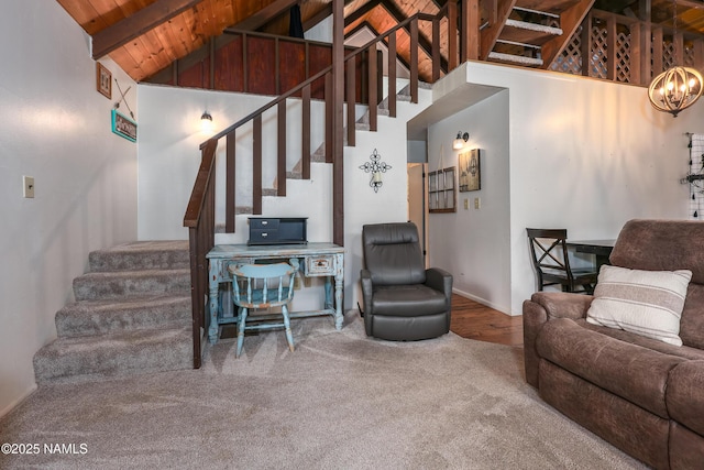 living area featuring beam ceiling, stairs, wood ceiling, carpet flooring, and a notable chandelier