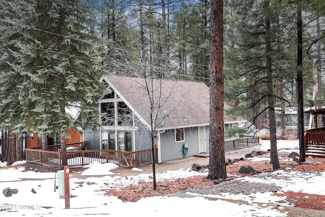 rustic home with a shingled roof and a deck