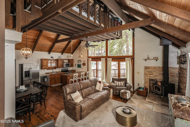 living area with beamed ceiling, wood ceiling, and a wood stove