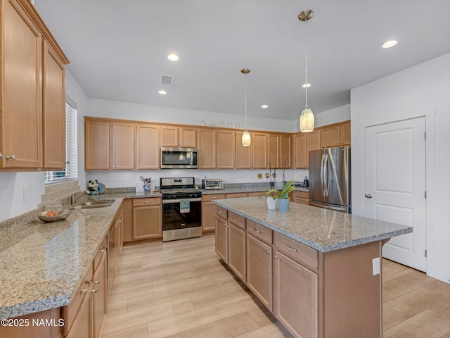 kitchen with light stone counters, recessed lighting, a sink, appliances with stainless steel finishes, and a center island