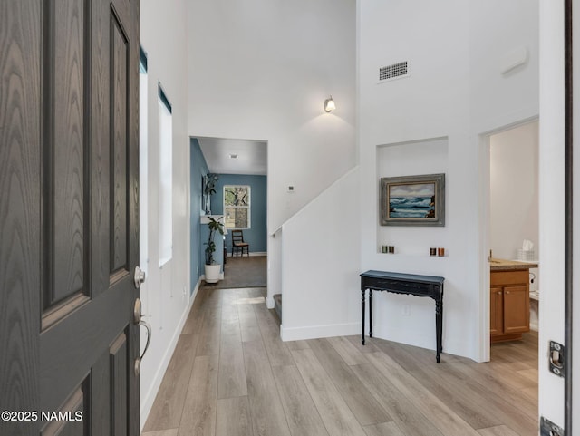 entryway featuring visible vents, a high ceiling, stairway, and light wood-style flooring