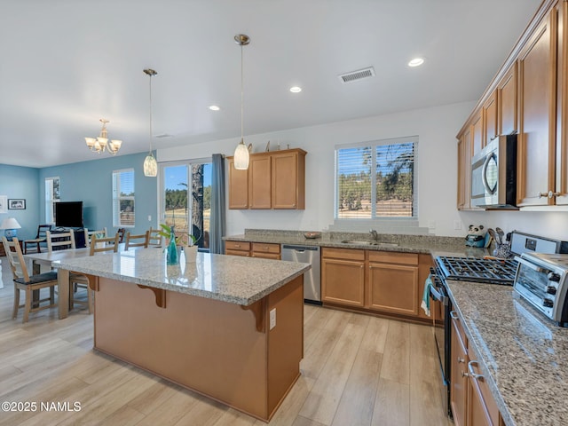 kitchen featuring stainless steel appliances, light wood-type flooring, visible vents, and a sink