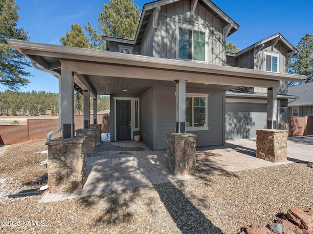 view of front of home featuring board and batten siding, fence, and a garage