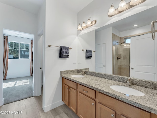 bathroom featuring a sink, a shower stall, baseboards, and double vanity