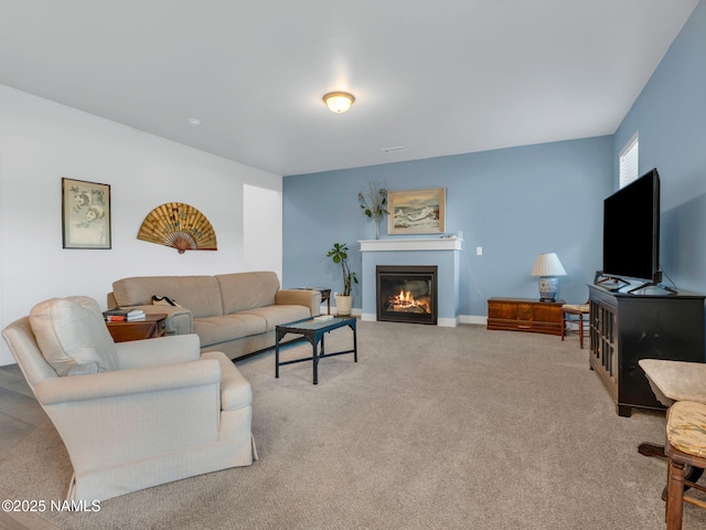 living room featuring carpet floors, a glass covered fireplace, and baseboards