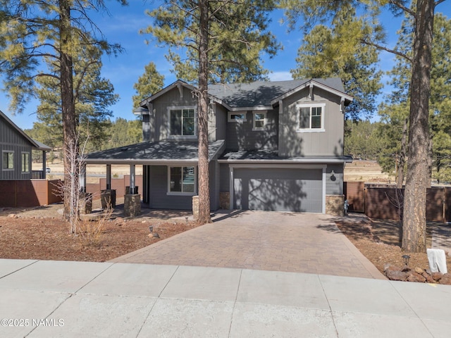 view of front of home with decorative driveway, covered porch, board and batten siding, fence, and a garage