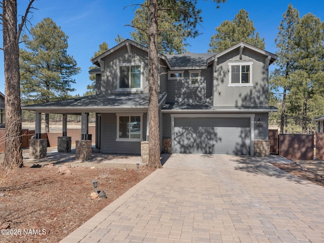 view of front of home with decorative driveway, a porch, an attached garage, board and batten siding, and fence