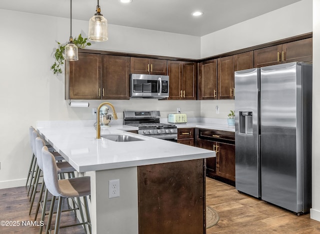 12296 Curtis Ct, Bellemont, AZ 86015 - kitchen with appliances with stainless steel finishes, dark brown cabinets, a peninsula, light countertops, and a breakfast bar