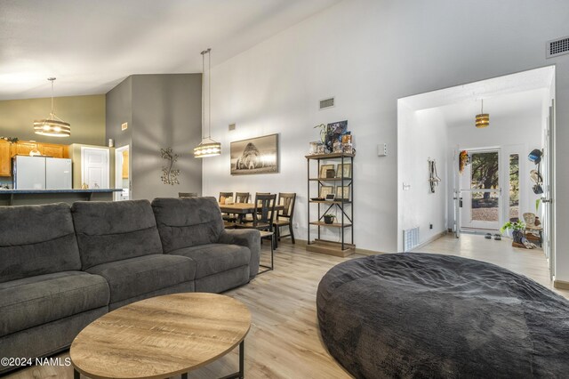 living room featuring light wood-type flooring and high vaulted ceiling