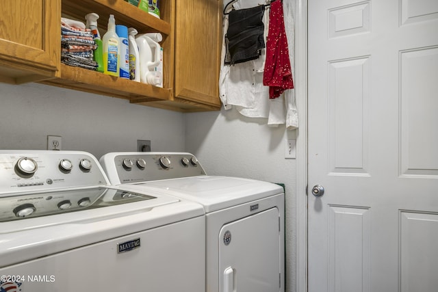 washroom with washer and dryer and cabinets