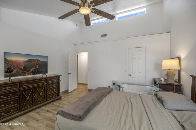 bedroom with ceiling fan, a high ceiling, and light wood-type flooring