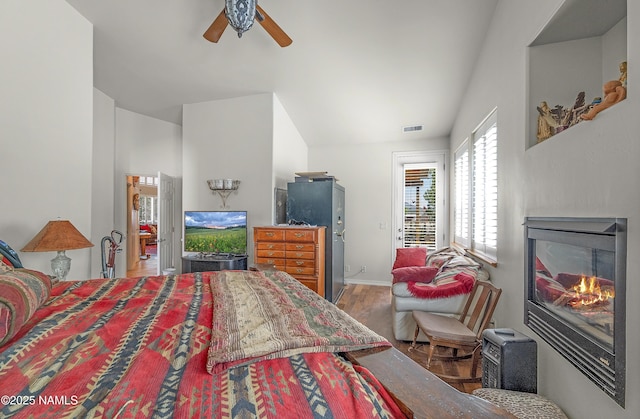 11267 N Lilac Ln, Flagstaff, AZ 86004 - bedroom featuring wood finished floors, a glass covered fireplace, lofted ceiling, a ceiling fan, and baseboards