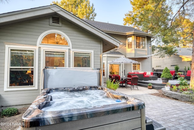 rear view of house with a patio area, an outdoor hangout area, and a hot tub