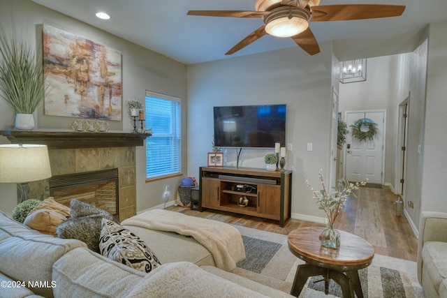 living room featuring ceiling fan, light hardwood / wood-style flooring, and a tiled fireplace