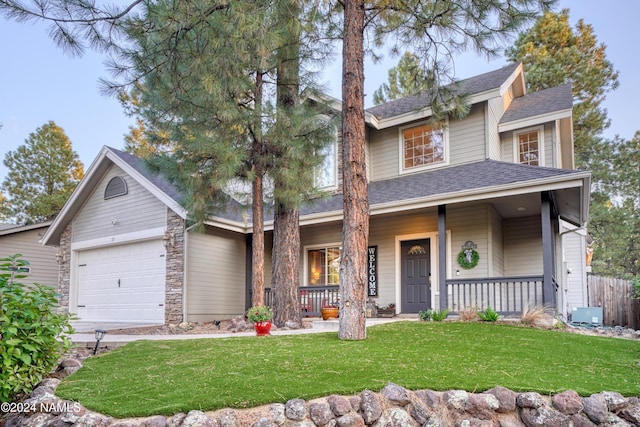 view of front of home featuring a garage, covered porch, and a front yard