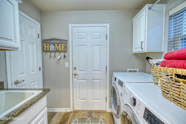 laundry area with washing machine and dryer, light hardwood / wood-style flooring, cabinets, and sink