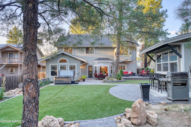 rear view of property with a lawn, a patio, and a hot tub