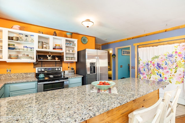 kitchen with open shelves, stainless steel appliances, a kitchen breakfast bar, and light stone countertops