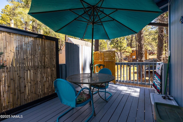 wooden deck featuring an outbuilding and outdoor dining area