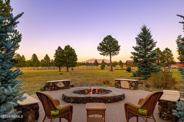 patio terrace at dusk with an outdoor fire pit and a rural view