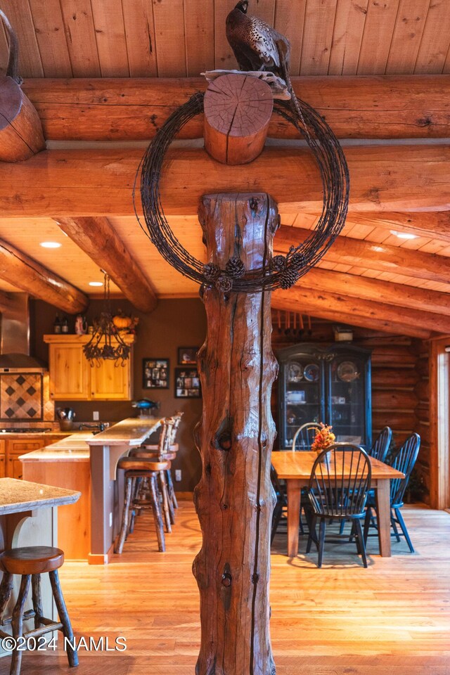 dining room with beamed ceiling, log walls, light hardwood / wood-style floors, and wooden ceiling