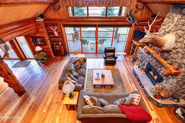 living room featuring wood-type flooring, beamed ceiling, a fireplace, rustic walls, and high vaulted ceiling