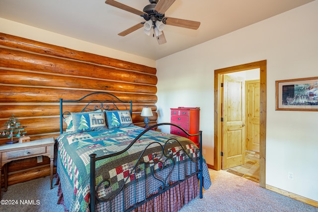 carpeted bedroom featuring connected bathroom, rustic walls, and ceiling fan