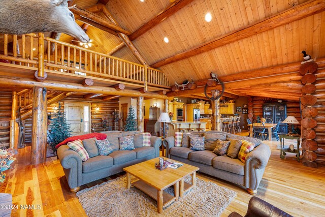 living room featuring beamed ceiling, wooden ceiling, rustic walls, high vaulted ceiling, and light hardwood / wood-style flooring