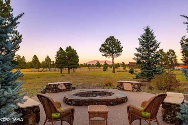 patio terrace at dusk featuring an outdoor fire pit and a rural view